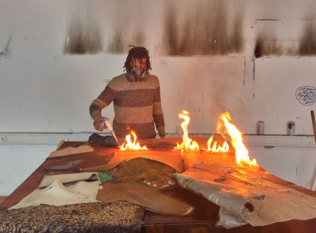 Alexandre Diop burning one of his canvases with a blow torch 