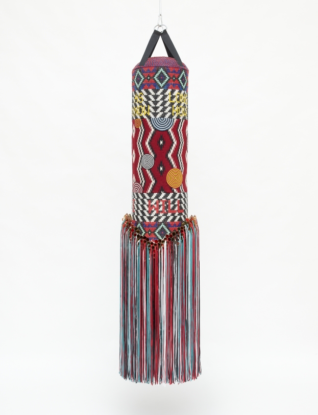 Jeffrey Gibson I WILL SURVIVE, 2020 Punching bag, trading post carpet, acrylic felt, artificial sinew, glass beads, copper and brass coated tin jingles, nylon fringe, nylon thread, cotton thread, cotton satteen fabric 87 x 20 x 20 in (221.0 x 50.8 x 50.8 cm)